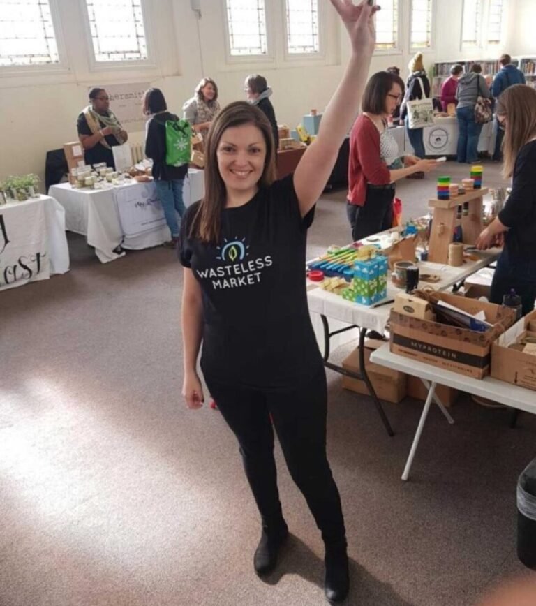 Teresa standing among indoor market stalls wearing a Wasteless Market t-shirt