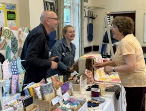 Stallholders enjoying a laugh with a customer at a market
